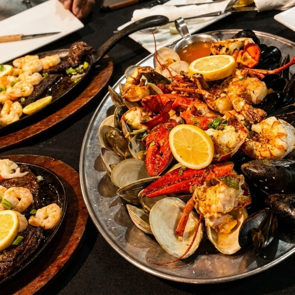 A large platter of seafood, including lobster, shrimp, mussels, and clams, with lemon slices.
