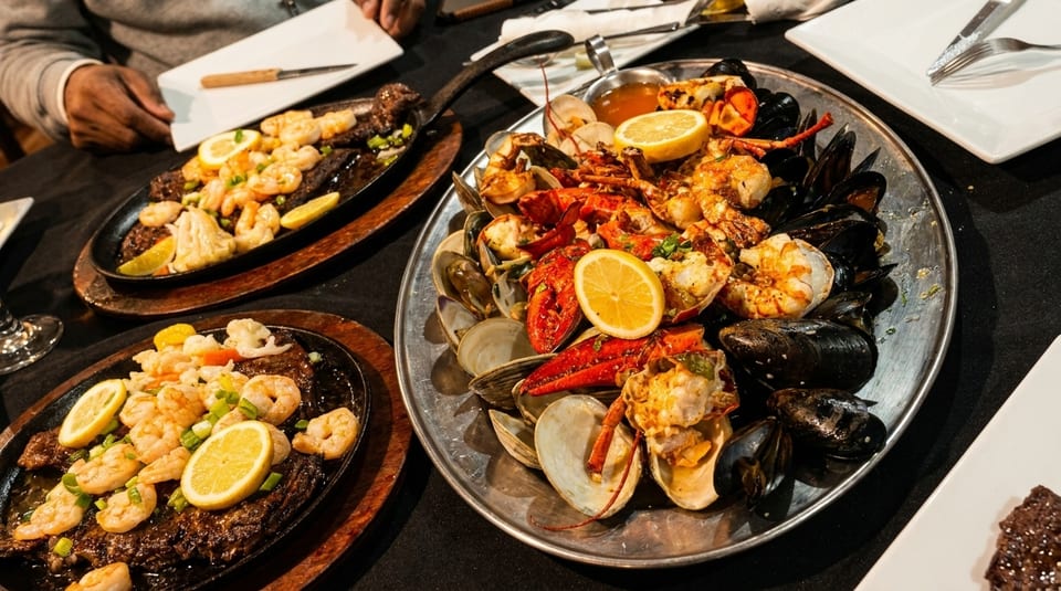 A large platter of seafood, including lobster, shrimp, mussels, and clams, with lemon slices.